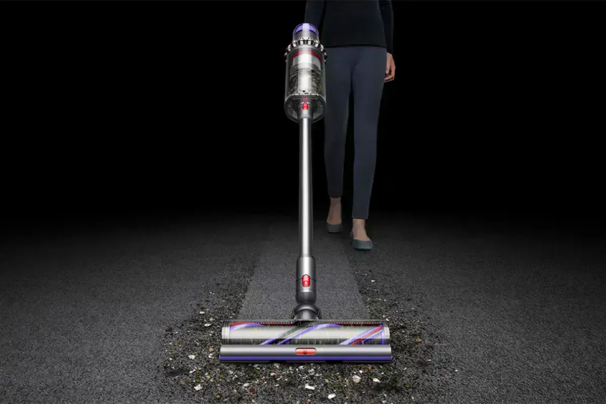 жінка збирає сміття на килимі пилососом dyson outsize plus