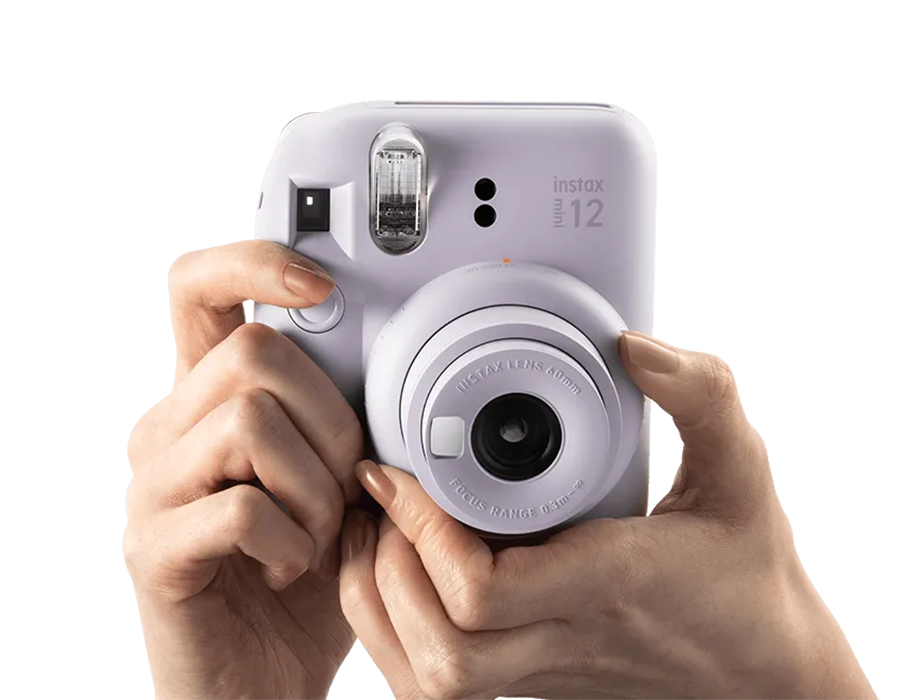 Користувач тримає Fujifilm Instax Mini 12, демонструючи поворот об’єктива