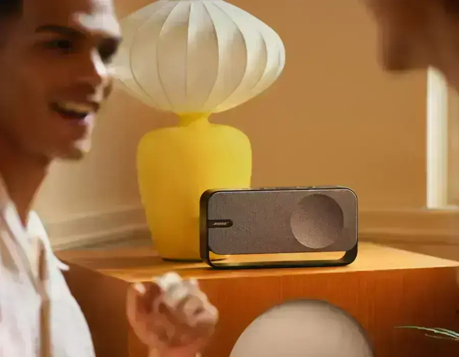 Колонка Bose SoundLink Home на тумбі біля вазона у вітальні