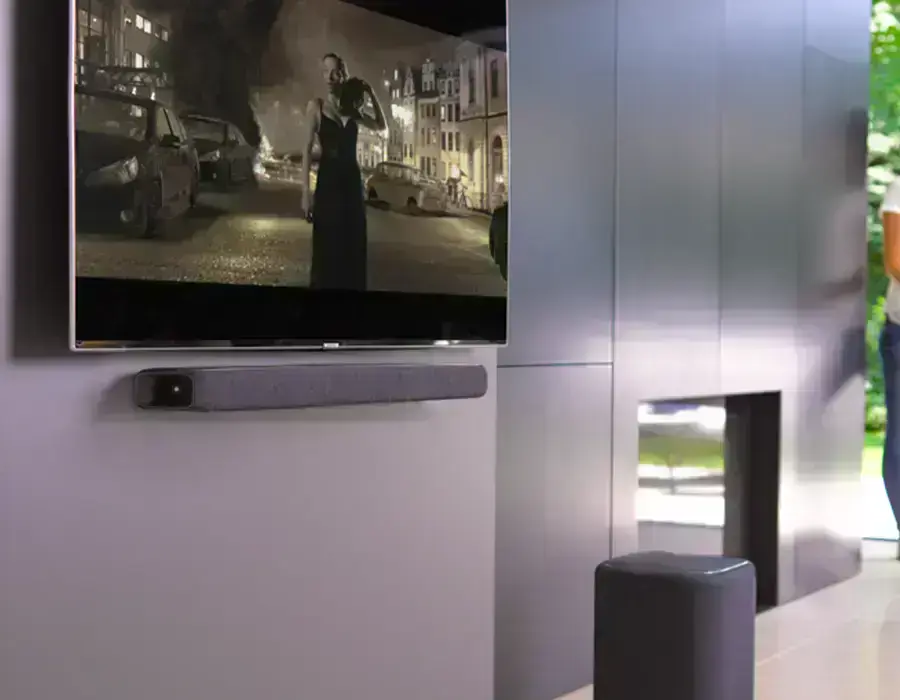 Саундбар Harman Kardon Enchant 800 на тумбі під телевізором в інтер’єрі вітальні